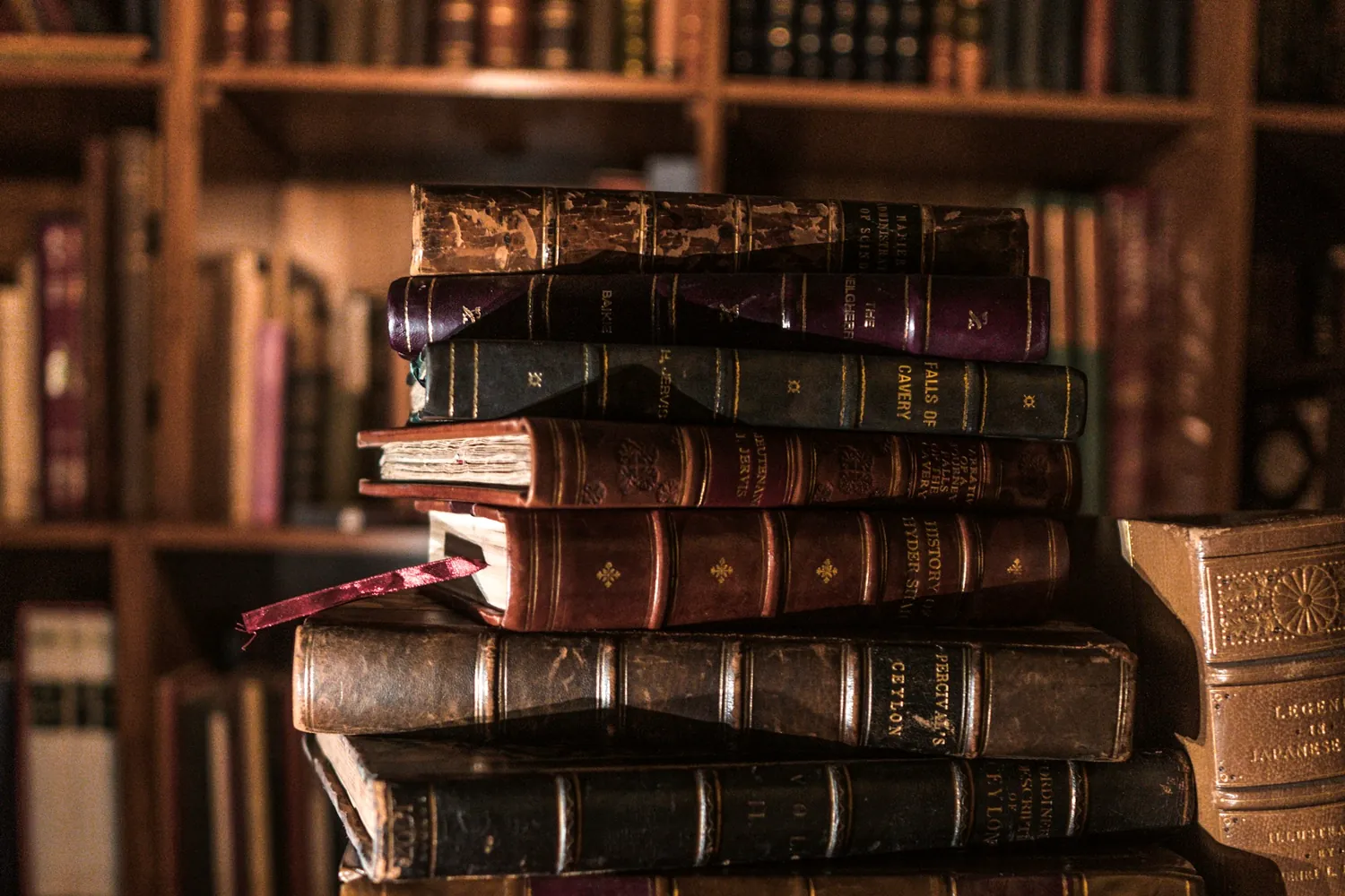 Une pile de livres anciens reliés, posée sur un tapis rouge
